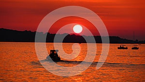 Fishermen on sea at red sunset