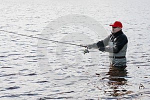 Fishermen spin fishing using chest waders