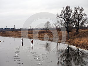 Fishermen on the thin ice of the river in autumn