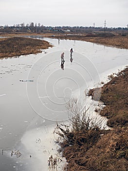 Fishermen on the thin ice of  river in autumn