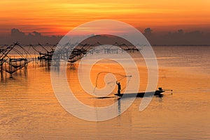 fishermen throwing fishing net from his boat early morning in the freshwater lake of Phatthalung province, Thailand