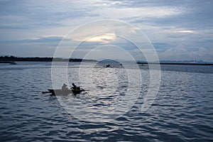 Fishermen on tiny fishing boat on the sea before sunrise