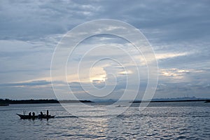 Fishermen on tiny fishing boat on the sea before sunrise