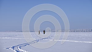 Fishermen walking along the frozen lake. Winter fishing