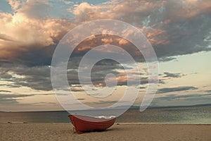 Fishermens boat at seacoast, on sand at sunset with horisont sea on background. Fishing boat on beach in evening. Travel photo