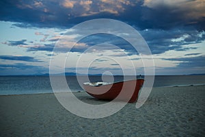 Fishermens boat at seacoast, on sand at sunset with horisont sea on background. Travel and rest concept. Background of