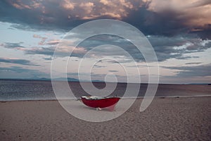 Fishermens boat at seacoast, on sand at sunset with horisont sea on background. Background of sea with waves and sky with clouds photo