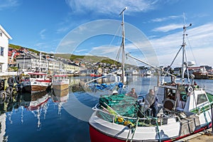 Fishers boat with two fishmen in moored in the harbor of Honningsvag city in Mageroya island.  Nordkapp Municipality in Finnmark