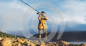 Fishery concept, beard fisherman hold in hands fishing rod, man enjoy hobby sport on evening lake, person catch fish on background