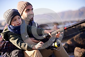 These fishes stand no chance. Shot of a loving father and son fishing by the sea.