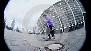 Fisheye view of sporty skater guy balancing on skateboard on city street.