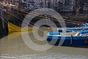 Fishing beautiful blue boats, gear and catch on background of Castelo Real of Mogador in Essaouira old harbor