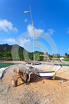 The fishing boat ashore, palm trees and hotels on a background.