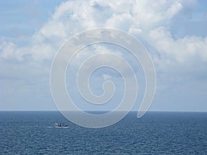 Fishing boat in asia on calm blue sea under fluffy cloudscape