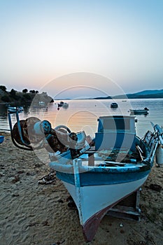 Fishing boat on a beach in front of ruins of a roman fortress at sunset, Sithonia