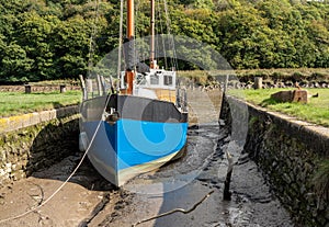 Fishing boat beached in mud by tidal River Tamar in Devon