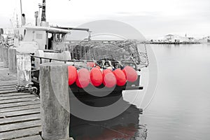 Fishing boat with bright pink buoys tied to stern rail at pier in Riverton
