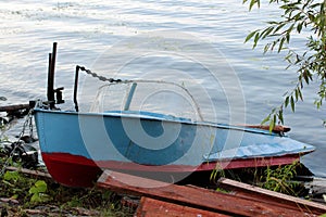 Fishing boat in a calm lake water/old wooden fishing boat/ wooden fishing boat in a still lake water