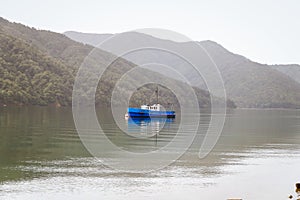 Fishing boat in a calm lake water/old wooden fishing boat/ wooden fishing boat in a still lake water