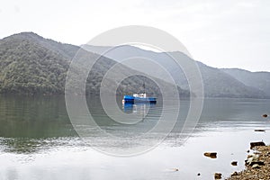Fishing boat in a calm lake water/old wooden fishing boat/ wooden fishing boat in a still lake water