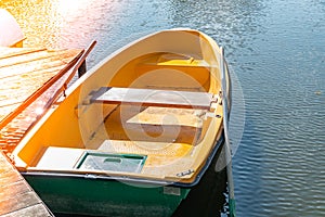 Fishing boat in calm lakes. Old wooden fishing boat. Wooden boat in still lake water at sunset