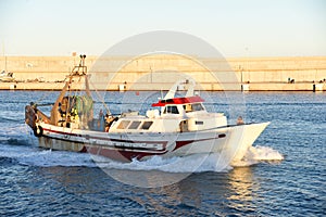 Fishing boat enters the in La Marina de Valencia. Fishermen on a fishing boat deliver the caught fish to the port.