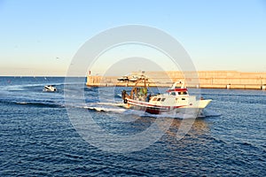 Fishing boat enters the in La Marina de Valencia. Fishermen on a fishing boat deliver the caught fish to the port.