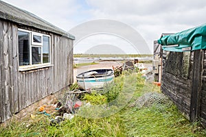 Fishing boat between fishing huts at Brancaster Staithe