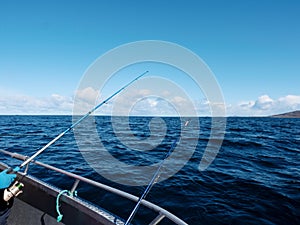 Fishing boat with fishing rods floating in open sea. Background beautiful sky. Sport fishing