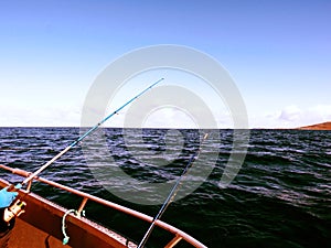 Fishing boat with fishing rods floating in open sea. Background beautiful sky. Sport fishing