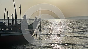 Fishing boat floats on water in palafito harbour at sunset