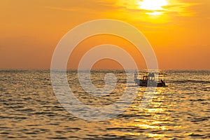 A fishing boat goes out to sea at sunset