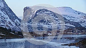 Fishing boat and huge Mountain at Sundstraumen on the Lofoten in winter in Norway at sunset