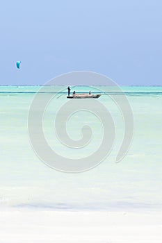 Fishing boat and a kite surfer on picture perfect white sandy beach with turquoise blue sea, Paje, Zanzibar, Tanzania. photo