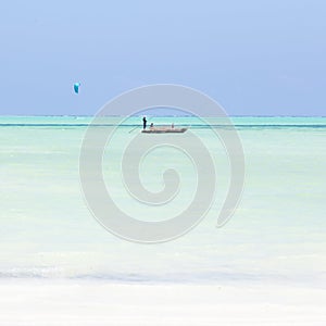 Fishing boat and a kite surfer on picture perfect white sandy beach with turquoise blue sea, Paje, Zanzibar, Tanzania. photo
