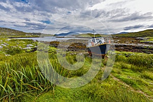 Fishing boat on land in a picturesque environment in front of an inlet at low tide in the landscape of the `Isle of Harris and Lew