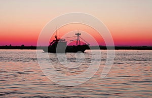 Fishing boat leaving port at nightfall