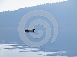 Fishing boat on misty lake silhouette