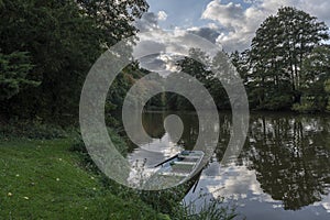 A fishing boat moored at the bank of a river at sunset