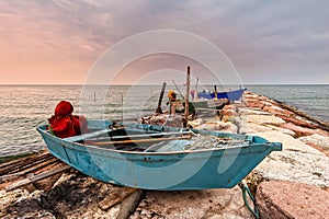 Fishing boat moored on cliff at sunset.