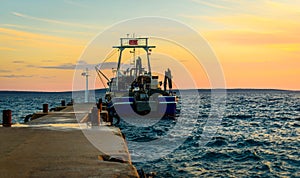 Fishing boat moored or docked at pier in sunset