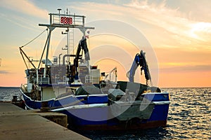 Fishing boat moored or docked at pier in sunset