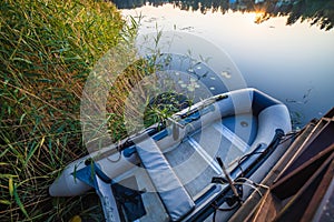 Fishing boat moored nearby the pier on calm water lake