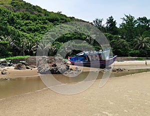 The fishing boat moored on the sand beach in the jungle