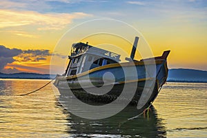 A fishing boat moored at the shore on a beautiful sunrise