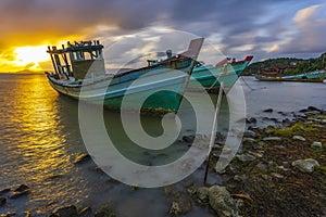 A fishing boat moored at the shore on a beautiful sunrise