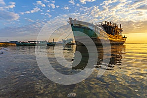 A fishing boat moored at the shore on a beautiful sunrise