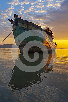 A fishing boat moored at the shore on a beautiful sunrise