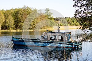 A fishing boat moored to the shore of the lake. Old fishermen& x27;s