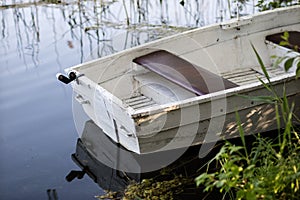 A fishing boat moored to the shore of the lake. Old fishermen& x27;s